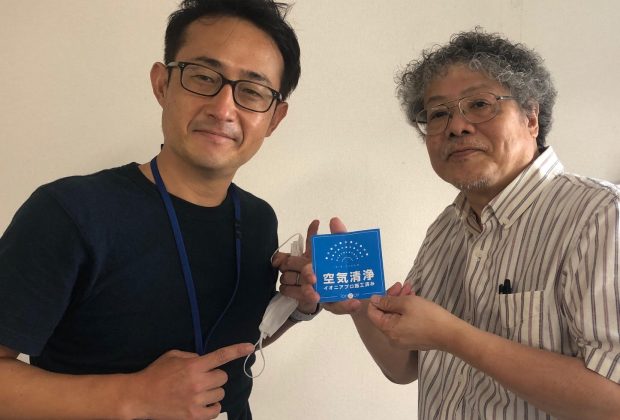 ロイヤル住建の岡田正幸社長から施工処理ステッカーを受け取るＦＭおおつの古田誠